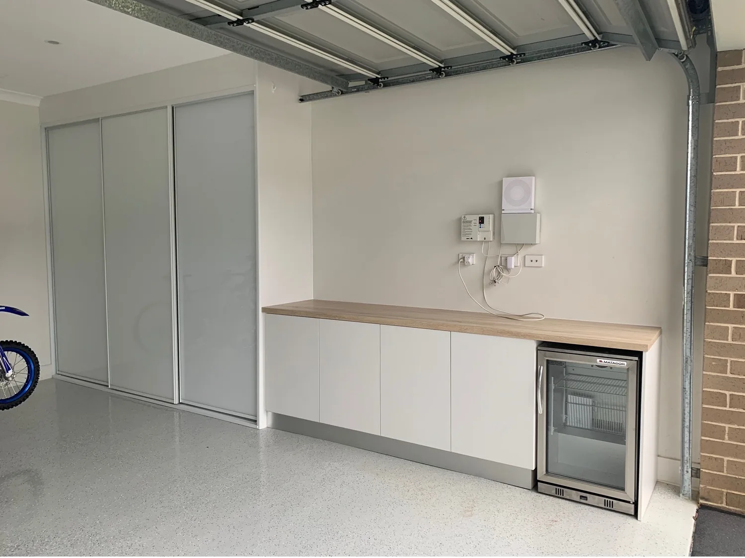 Custom garage cabinetry with benchtop and bar fridge